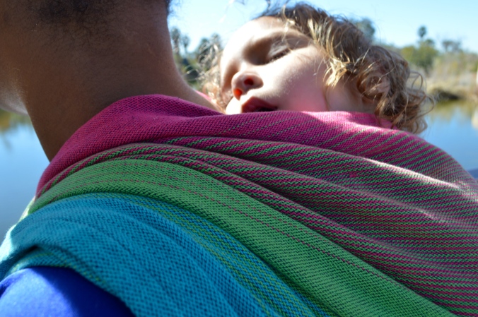close up shot of sleeping baby face on Momma's shoulder with the wrap pleated at her shoulder