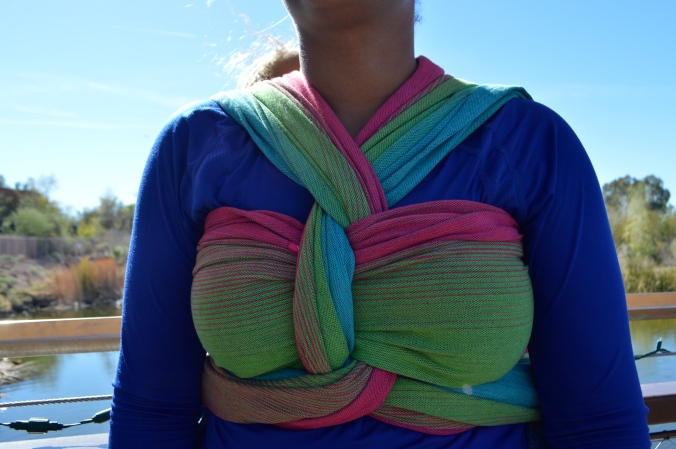 close up view of the finish in a pink, green, turquoise, and magenta wrap. The wrap twists at the neck as one tail passes over the chest pass and the other under the chest pass