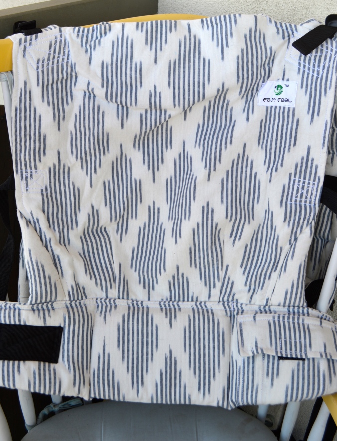 Image shows close up of the carrier showing a dominant white background with navy blue diamond Ikat pattern over the body, waistband, and shoulder straps of the carrier