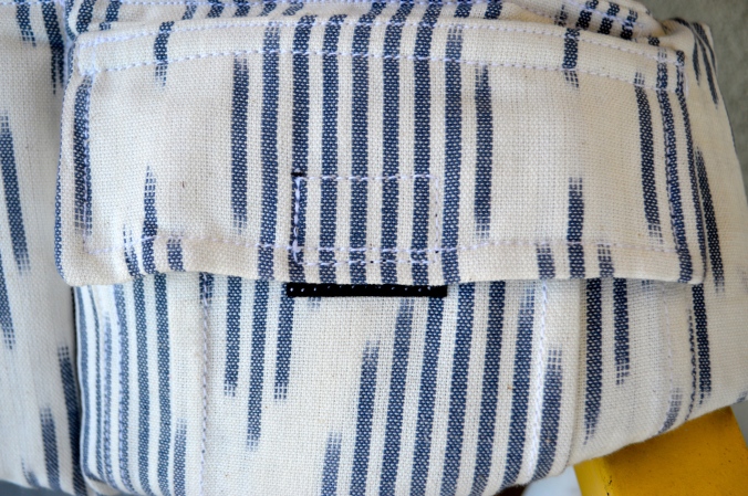 Image shows a close up on the pocket on the waistband. Closes with a velcro and is white and navy blue Ikat diamond design