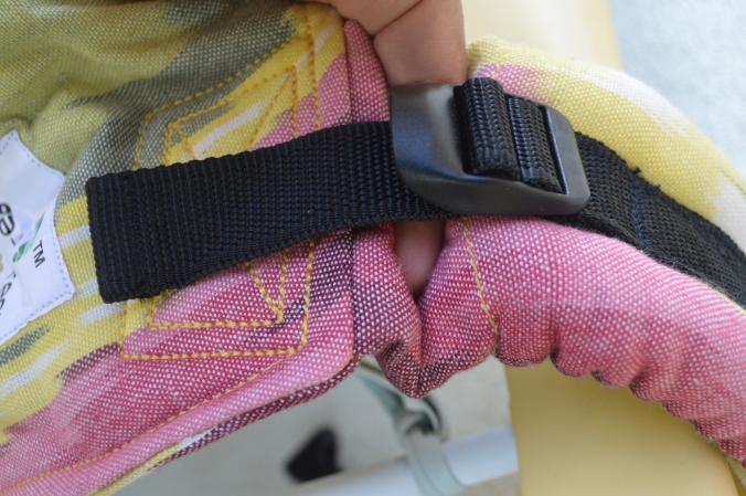 Image shows a hand pointing to the black ladder lock hardware on the adjuster at the top of the carrier shoulder strap.