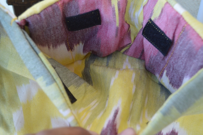 Image shows yellow, pink, and white pattern of the hood storage pouch inside the top of the carrier body