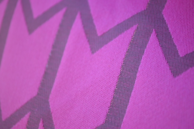 Very close up image showing the pink side of the wrap and a zoom in on one of the zig-zag stripes showing tiny little holes with light coming through