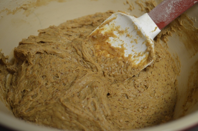 Image shows a light brown cookie dough in a ceramic bowl with a silicone spatula