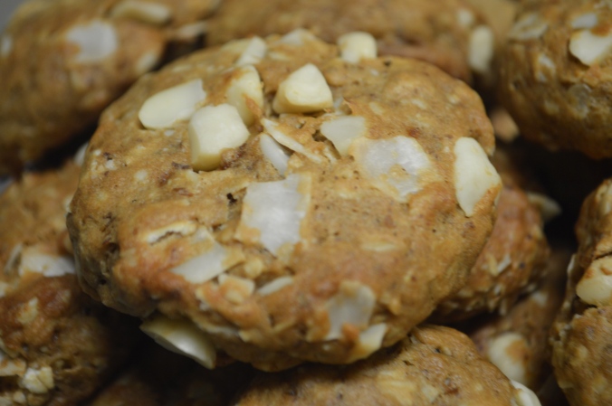 Close up image of baked cookies cooking on a plate with white macadamia nuts and large coconut flake