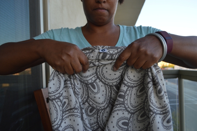Image shows the brown skin woman folding the wrap at one to two inch intervals end over end